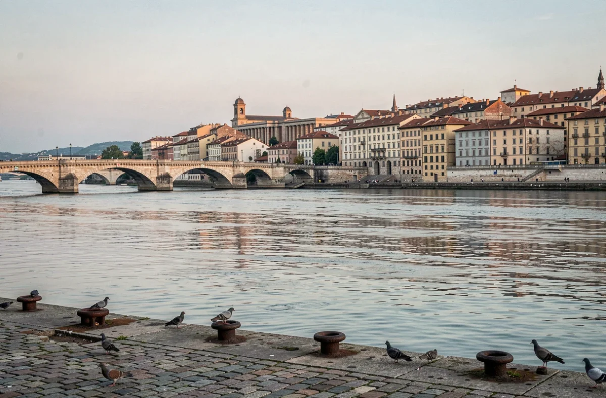 Vue sur le Rh&ocirc;ne &agrave; Lyon avec un pont historique en pierre et les toits de la vieille ville se refl&eacute;tant dans l'eau calme du fleuve